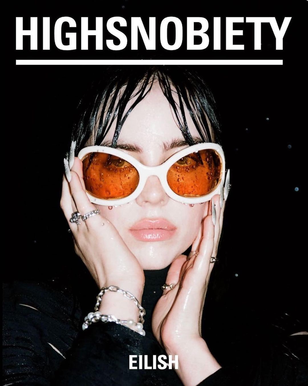 Close-up fashion magazine cover featuring a young woman with wet hair, wearing sunglasses, and jewelry against a black background.