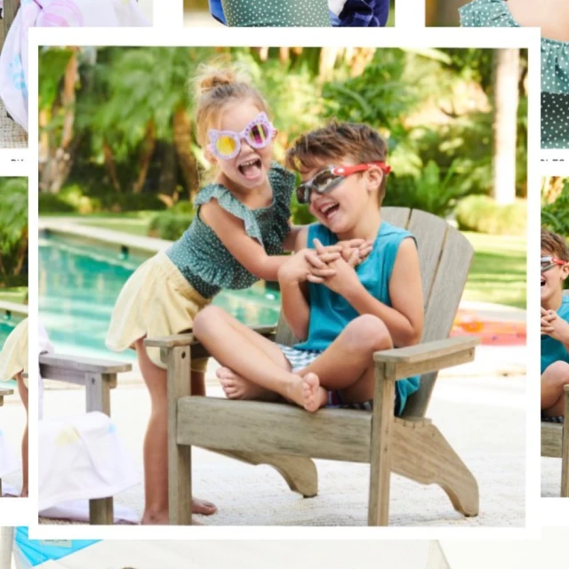 Two smiling kids, a girl and a boy wearing sunglasses, sit in an Adirondack chair near a swimming pool and lush green plants.
