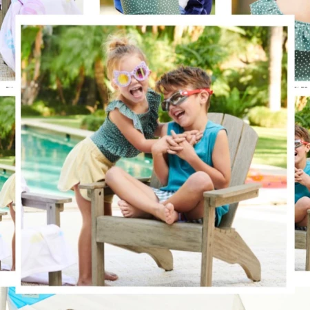 Two smiling kids, a girl and a boy wearing sunglasses, sit in an Adirondack chair near a swimming pool and lush green plants.
