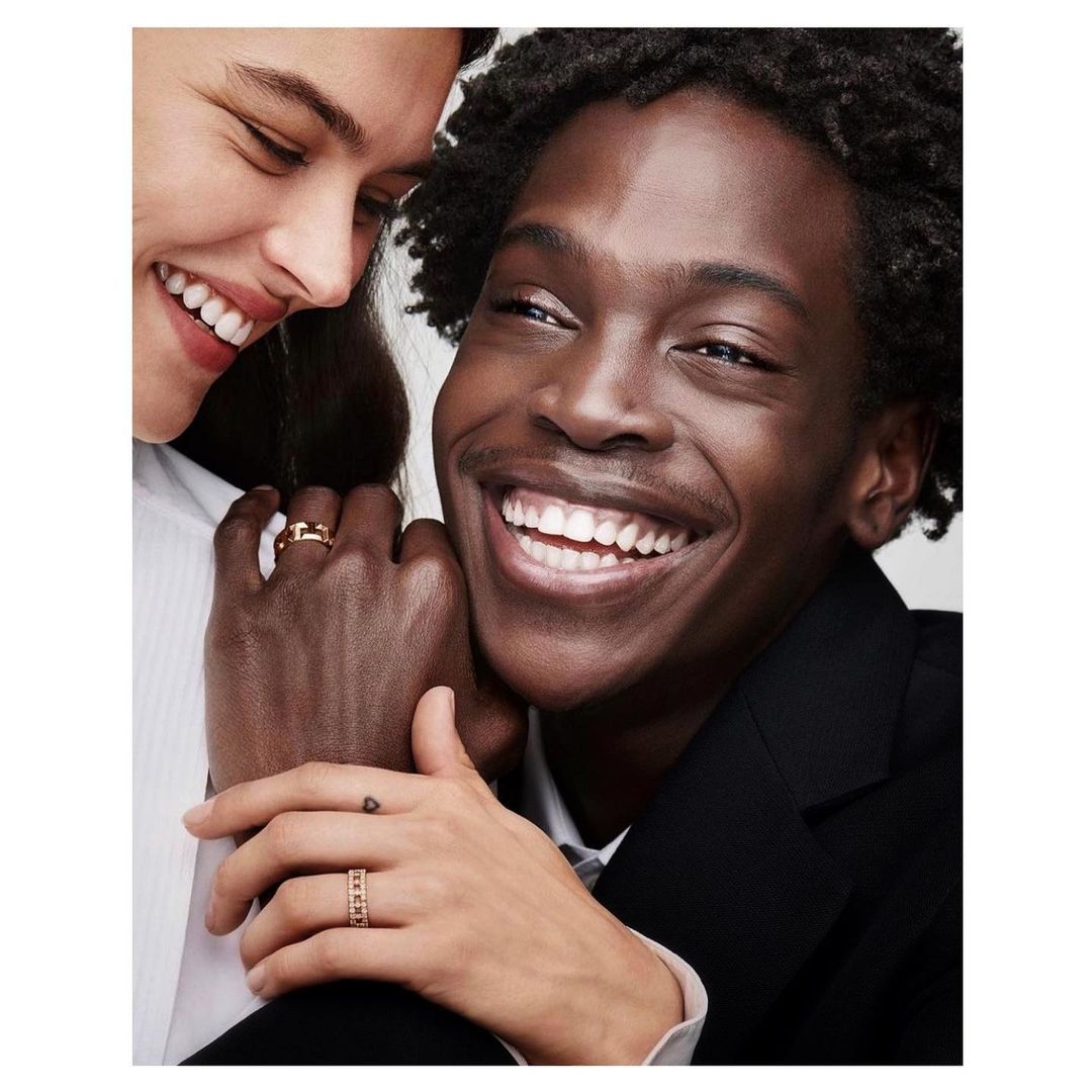 Close-up shot featuring two people smiling, showcasing a white adult female and a black adult male with rings on their fingers.