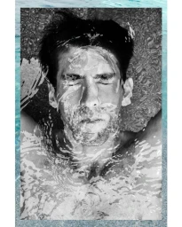 Close-up black and white portrait of a man floating in water with ripples distorting his face.