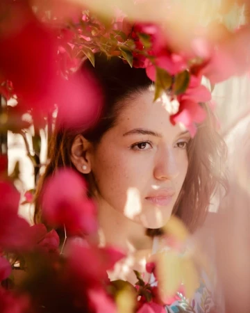 Portrait of a woman framed by bright pink bougainvillea blossoms, captured by photographer Dean Freeman.