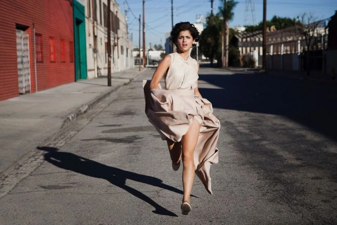 Woman in flowing beige dress running down an asphalt street by photographer Dean Freeman