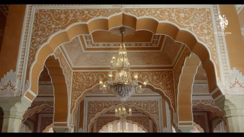 Ornate interior featuring arched doorways, detailed plasterwork, and elegant chandeliers, showcasing architectural grandeur.