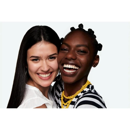 Two smiling young women with their cheeks touching against a bright white background, captured by photographer Dean Freeman.