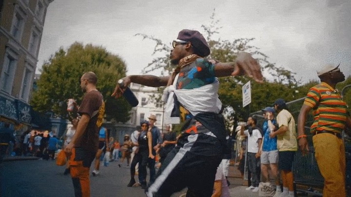 Man dances in a street crowd in an urban setting during daytime, showcasing vibrant energy and community.