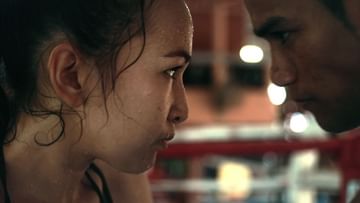 Close-up portrait of two Asian adults facing each other, with a boxing ring and blurred background, intense mood, and dramatic lighting.