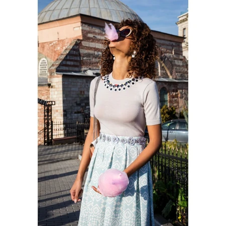 Woman wearing sunglasses holding pink cotton candy outdoors against an ancient stone building exterior