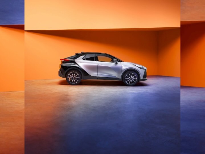 Sleek silver and black electric SUV in minimalist studio setting with vibrant orange wall, showcasing modern automotive design.