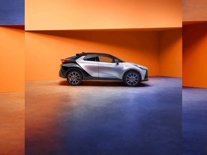 Sleek silver and black electric SUV in minimalist studio setting with vibrant orange wall, showcasing modern automotive design.