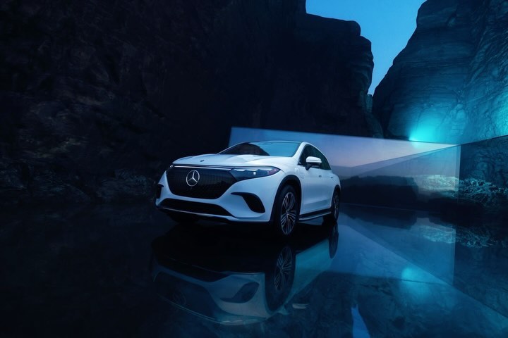 White Mercedes EQE SUV in a studio setting with artificial lighting, showcasing its sleek design and modern features in a promotional shot.