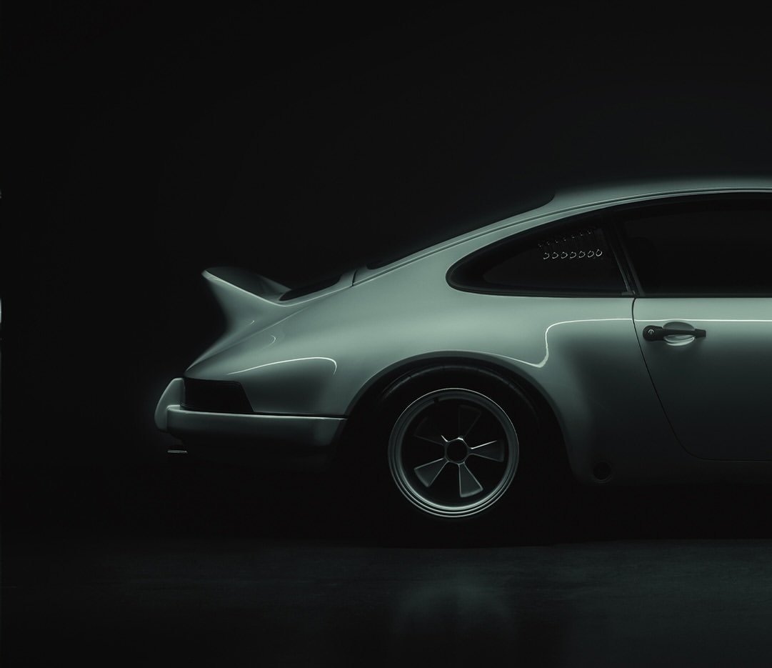 Sleek, side-view studio shot of a vintage silver sports car with black wheels, set against a deep, dark backdrop for automotive advertising.
