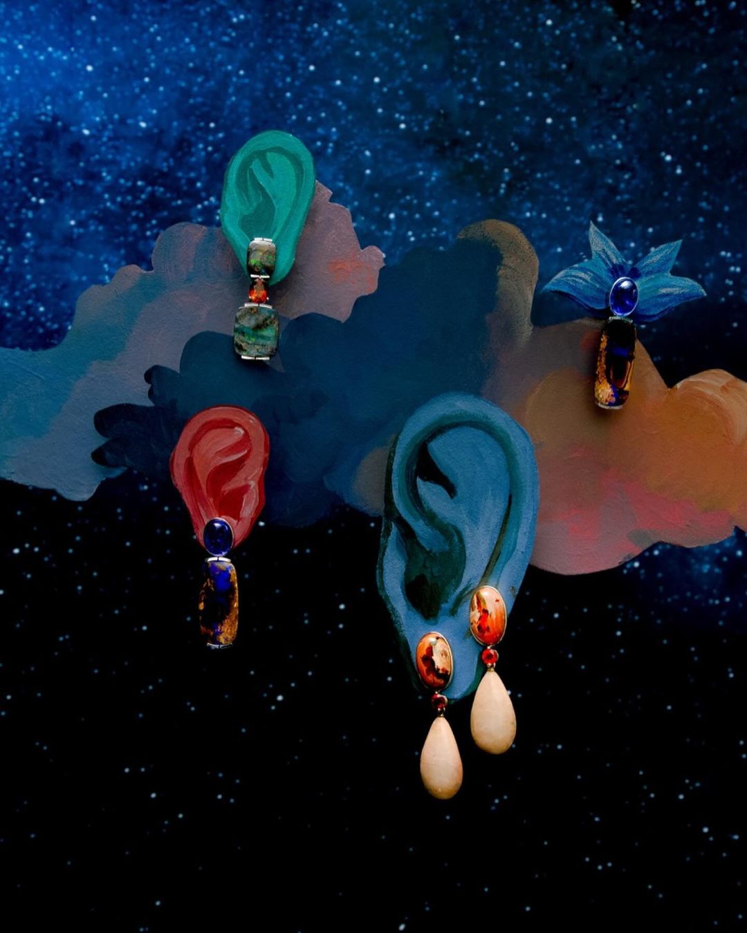 Whimsical composition features four painted ears adorned with earrings, set against a starry night sky and colorful cloud-like formations.