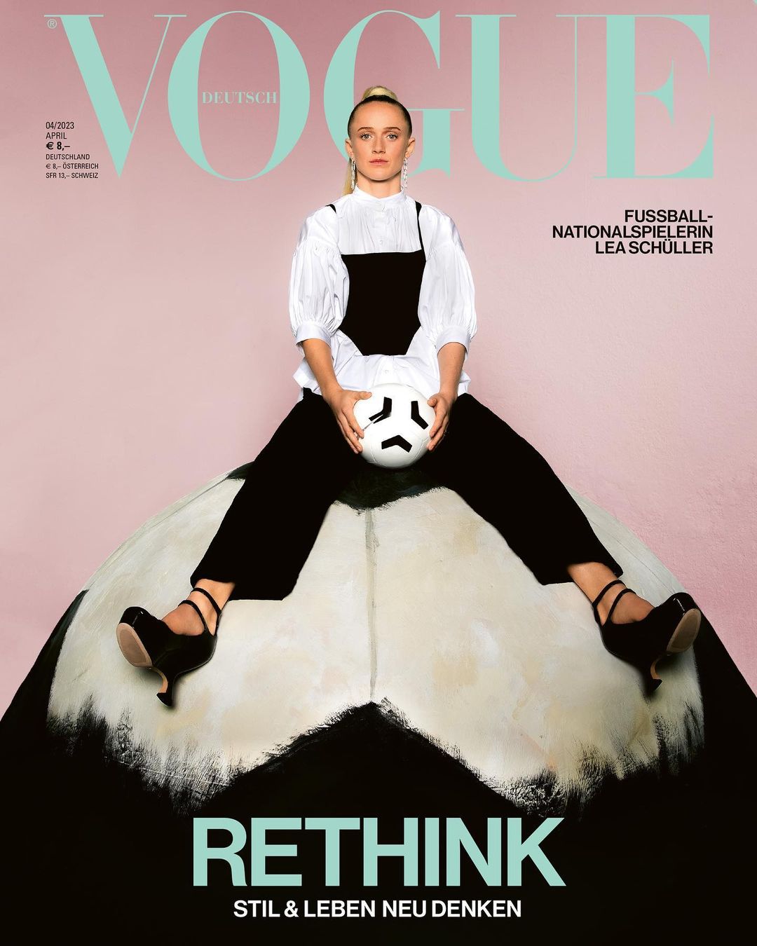 Vogue cover features a woman with a ball atop an oversized soccer ball, in a studio with a pink and black backdrop, and Vogue logo.