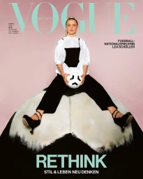 Lea Schuller seated on a large soccer ball holding a ball wearing white blouse and black trousers