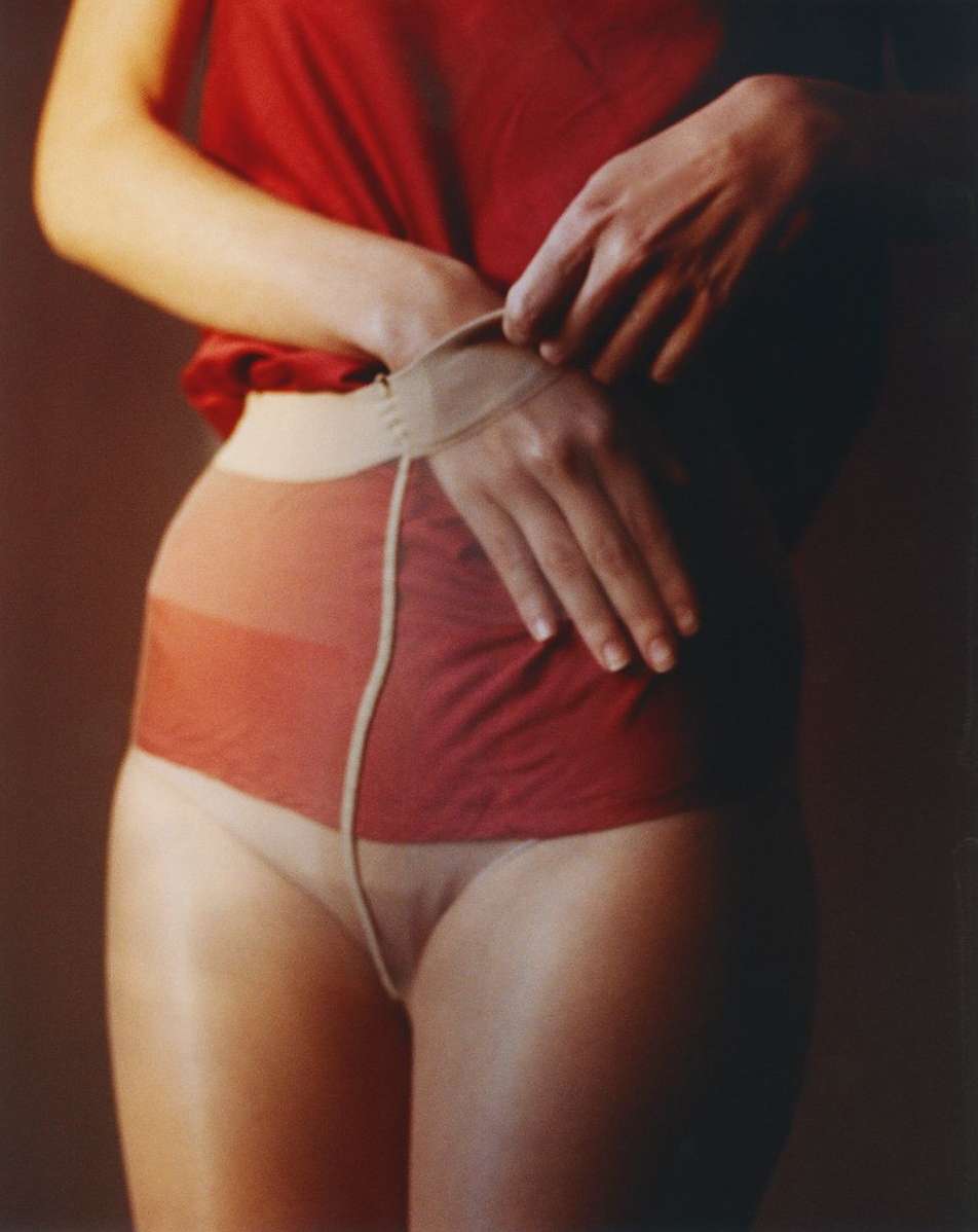 Close-up shot of a person's torso and hands adjusting sheer, two-tone tights, showcasing fashion and intimate apparel.