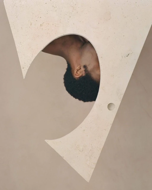 Abstract art with a close-up of an African-American man's head and neck framed by a large, triangular, beige architectural cutout.