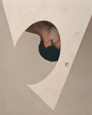 Abstract art with a close-up of an African-American man's head and neck framed by a large, triangular, beige architectural cutout.