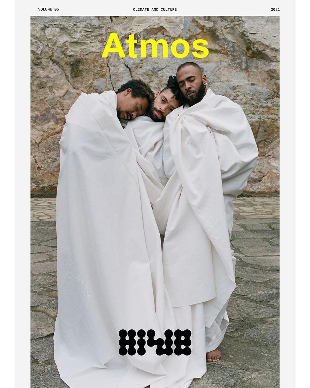 Magazine cover featuring three men wrapped in white cloth against a stone background, with bold yellow text "Atmos" at the top.