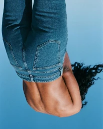 Inverted portrait of a person wearing blue denim jeans against a solid blue background