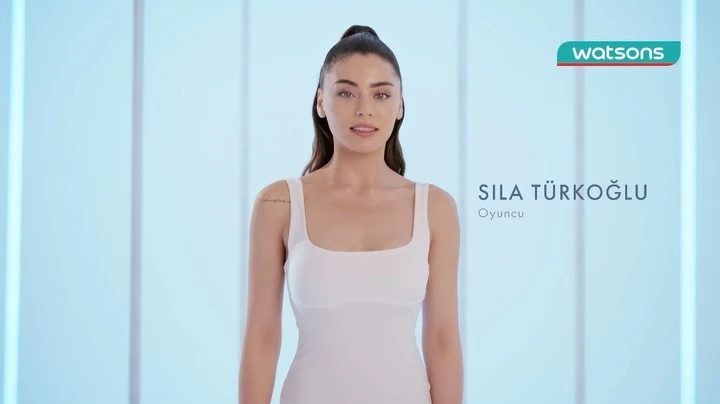 A woman in a white dress stands against a light blue background in a beauty or fashion context, with the Watsons logo visible.