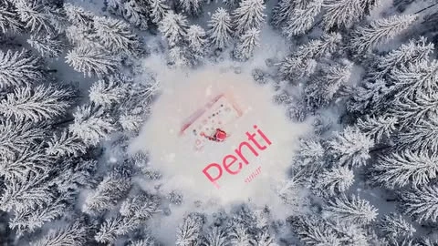 Aerial view of a snow-covered forest with a pink and white cosmetics product surrounded by winter trees dusted with fresh snow.