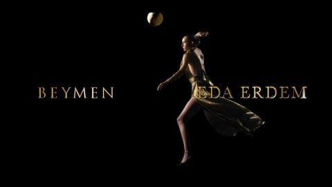 Athletic woman in gold dress plays volleyball on black background with 'Beymen Eda Erdem' text overlay, creating a striking sports fashion image.