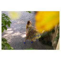 High-angle shot of a woman in a floral midi dress standing on a circular cobblestone courtyard, photographed by Dennis Golonka.