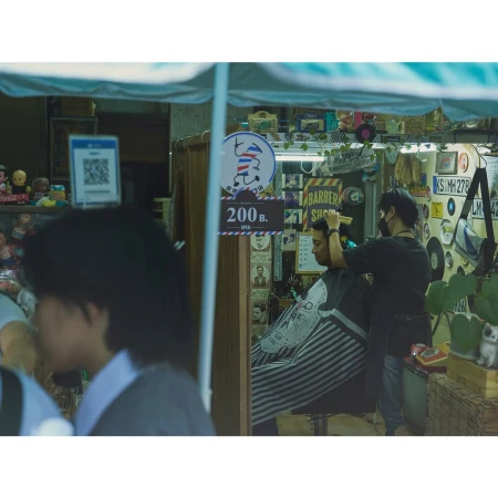 Barbershop scene features barber giving a haircut to a seated client; signage, records, and various decorations enhance the space.