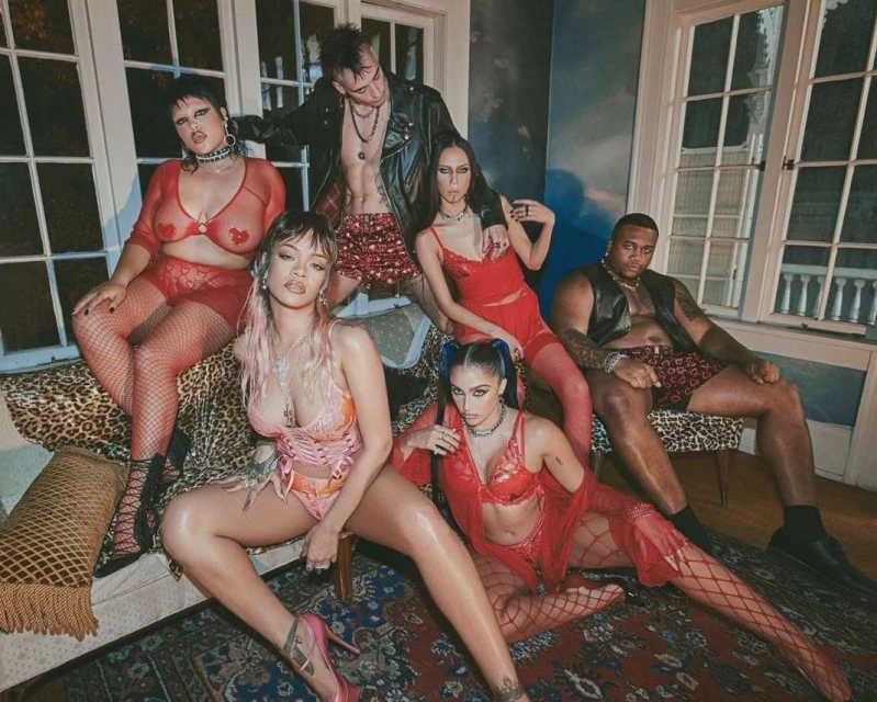 Group of six diverse models in lingerie pose together in a room with dark lighting and patterned rugs and furniture.