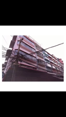 Angled low-angle shot of a multi-story building in an urban environment with electrical wires and architectural details.