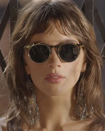 Close-up portrait of a woman wearing round dark sunglasses and long beaded earrings by photographer Dennis Leupold
