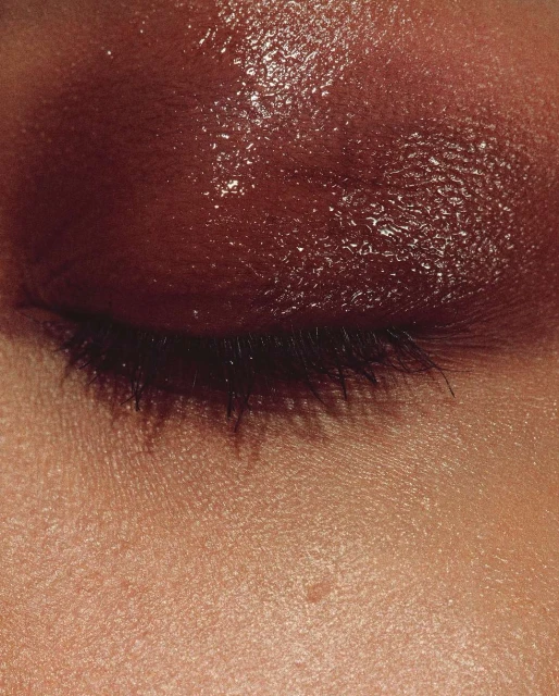 Close-up shot of a person's eye with brown eyeshadow and visible eyelashes, highlighting beauty and cosmetic trends.