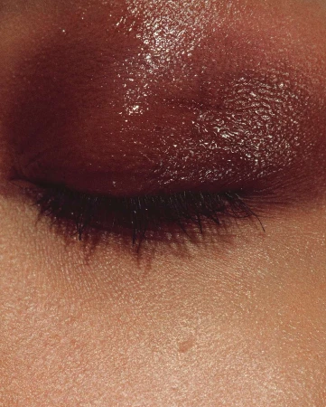 Close-up shot of a person's eye with brown eyeshadow and visible eyelashes, highlighting beauty and cosmetic trends.