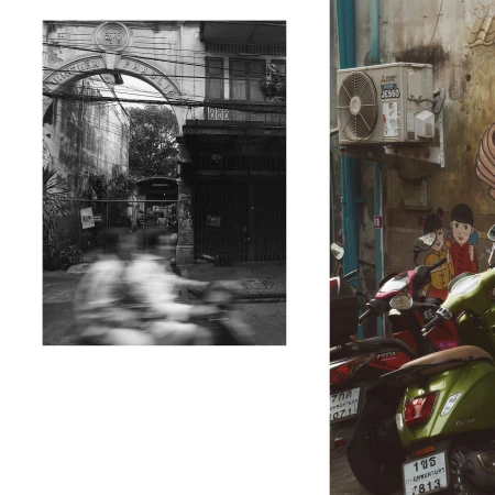 Monochrome street scene featuring blurred figures on a motorbike passing under an archway and parked motor scooters.