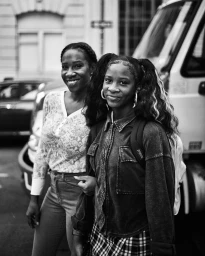 Black-and-white street portrait of two women walking outdoors near a vehicle, captured by photographer Devin Allen in New York.