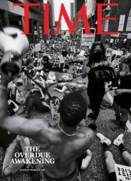 High-angle black and white protest photograph featuring a shirtless man holding a megaphone in the foreground, shot by Devin Allen.