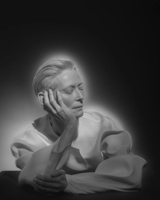 Monochrome portrait of an adult woman with short blond hair, gazing to the right with her face resting on her left hand.