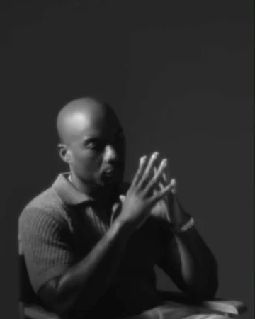 Black and white portrait of a bald man seated with hands clasped by photographer Devin Yalkin in New York