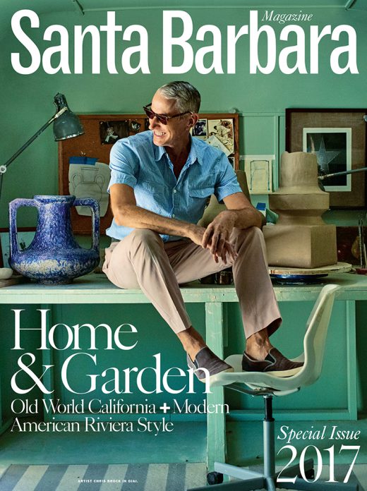 Magazine cover featuring a mature man in a casual outfit sitting on a desk with pottery and an office chair in a light green room.