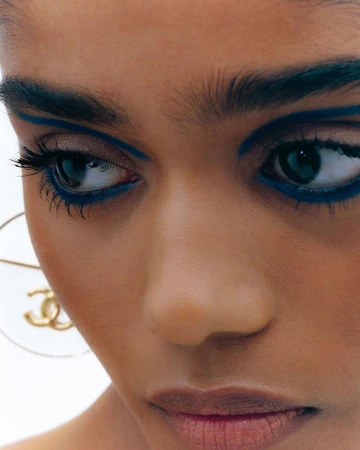 Extreme close-up portrait of a woman with bold blue graphic eyeliner and gold hoop earrings by photographer Dhruvin in Mumbai.