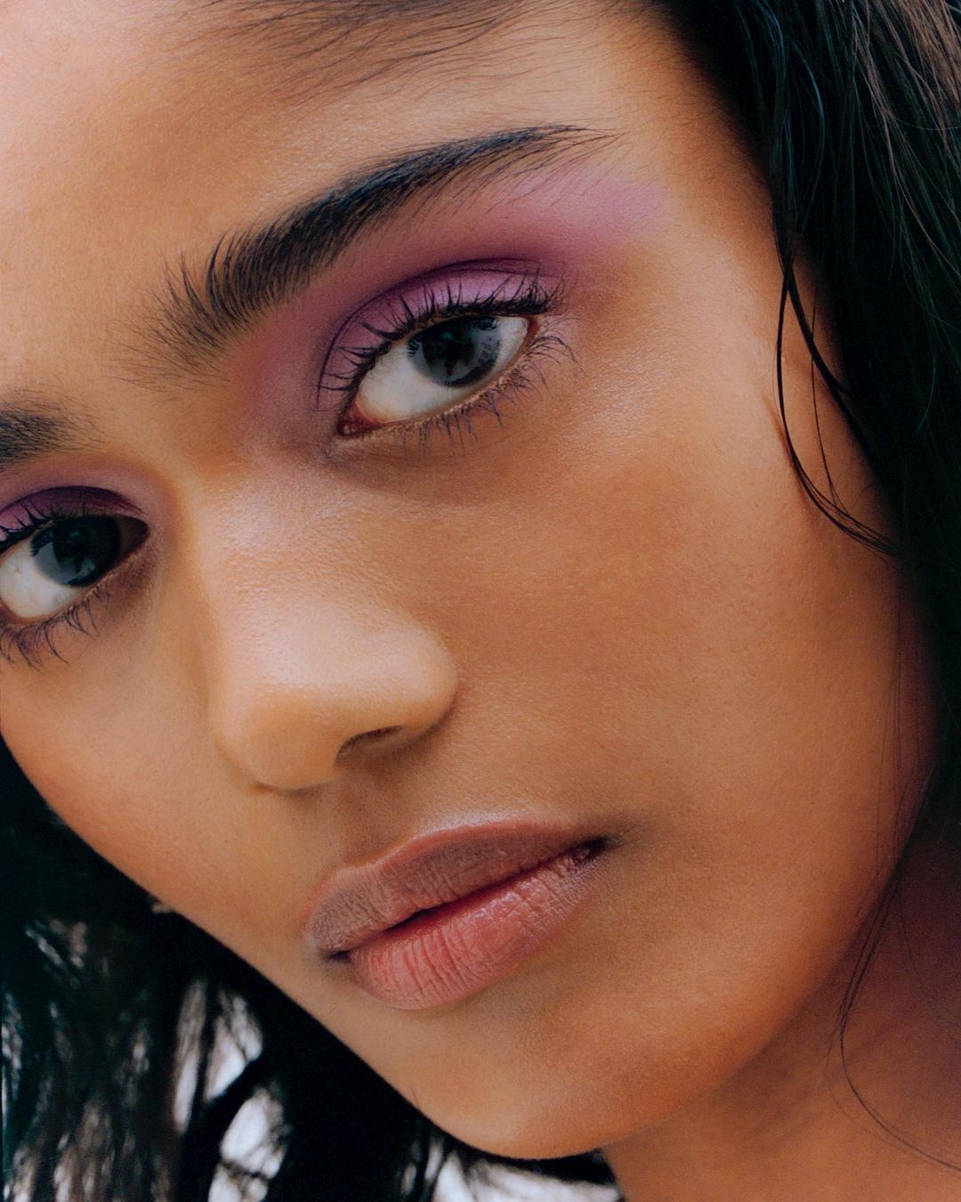 Close-up portrait of a woman with dramatic purple eyeshadow and dark wet-look hair captured by Dhruvin.