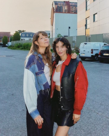 Two women standing outdoors in a parking lot, photographed by Diane Sagnier in Paris.