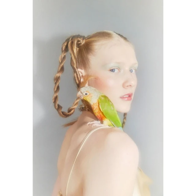 A portrait shot of a woman with red hair wearing a white top against a grey background, showcasing soft studio lighting.