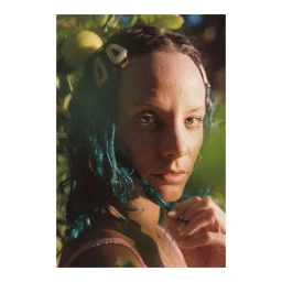 Portrait of a woman with dark hair holding a strand against natural foliage in Paris by Diane Sagnier