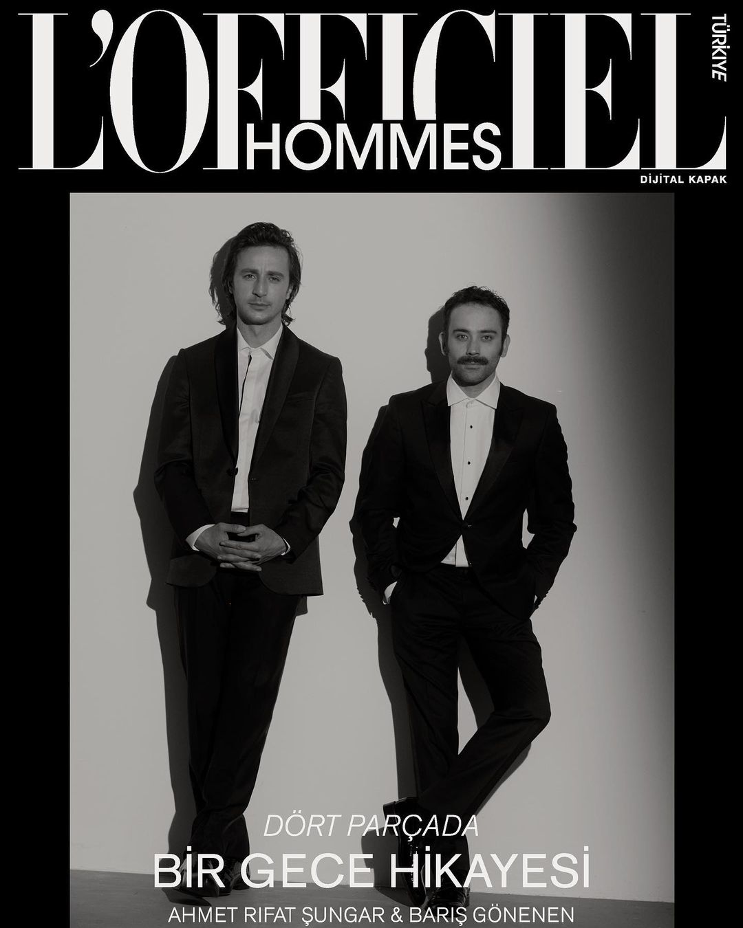 L'Officiel Hommes magazine cover featuring two adult men in dark suits posing in front of a solid white background in a studio setting.