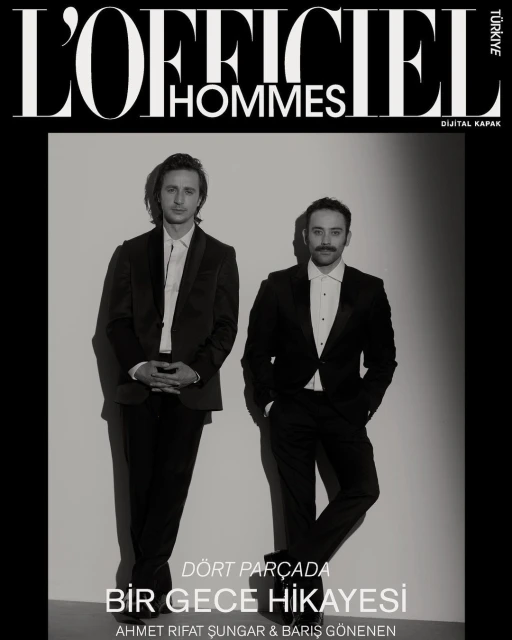 L'Officiel Hommes magazine cover featuring two adult men in dark suits posing in front of a solid white background in a studio setting.