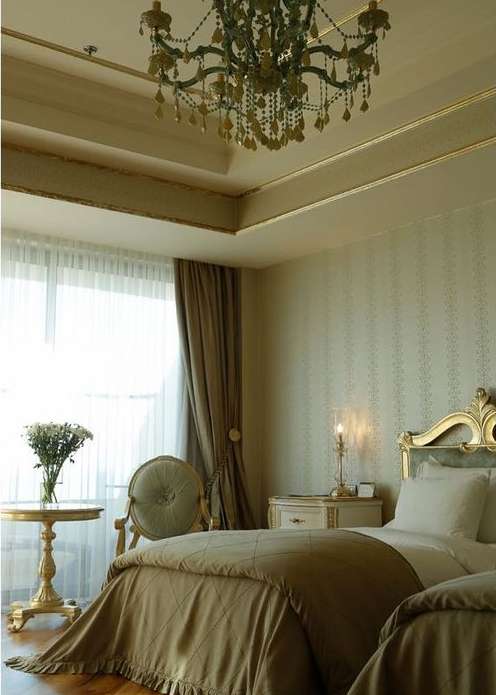 Elegant bedroom interior with twin beds, decorative chandelier, and gold accents, capturing a luxurious and inviting atmosphere.