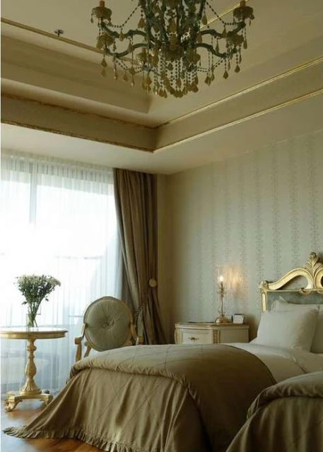 Elegant bedroom interior with twin beds, decorative chandelier, and gold accents, capturing a luxurious and inviting atmosphere.