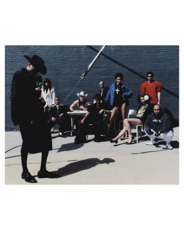 Group portrait of ten diverse models posing outdoors against a dark brick wall by photographer Diego Bendezu